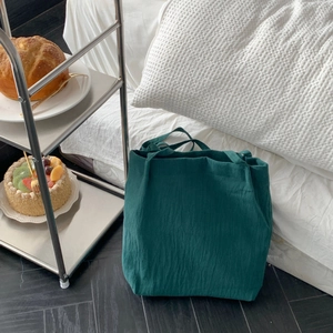 Detail of dark green washed linen tote bag with natural texture and soft handles