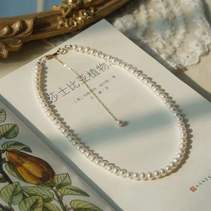 Detailed shot of baroque pearl pendant necklace with gold chain on vintage book