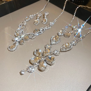 Detailed view of silver necklace and earring sets with teardrop and flower crystal pendants
