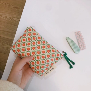 Detailed close-up of a floral cotton coin purse featuring a white zipper and green pull cord