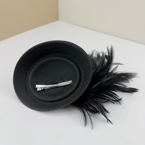 Detail view of the black feather fascinator hat showing the silver crocodile hair clip base