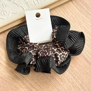 Detail of double-layer leopard print scrunchie with pleated black fabric texture on wood