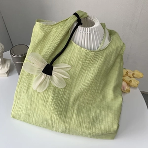 Detail of light green pleated tote bag with daisy pendant and stylish rope straps