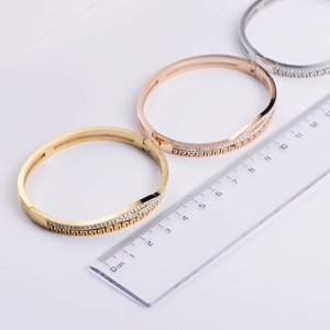 Detailed view of geometric Greek pattern bangles with cubic zirconia and scale measurement