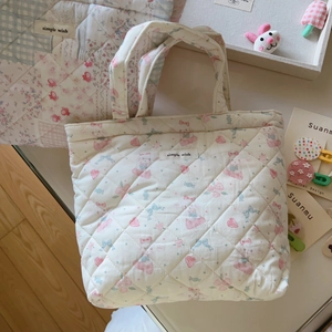 Quilted floral handbag with pastel patchwork and bow detail on a neutral table surface
