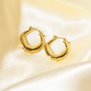Dettaglio di orecchini a cerchio spessi placcati oro 18K con trama a coste su raso