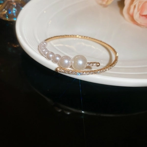 Detailed shot of gold cuff bracelet featuring gradient pearls and pave crystal accents