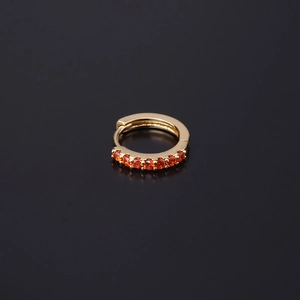 Macro detail of gold-plated hoop earring with seven sparkling orange zircon stones
