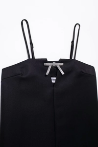 Détail de la robe noire à bretelles avec un nœud en strass étincelant sur l'encolure