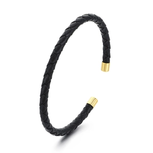 Bracciale a polsino in pelle intrecciata nera con punte in metallo dorato visto a 45 gradi