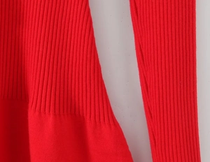 Close-up of red ribbed knit texture and fine stitching detail on a slim-fit dress