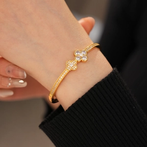 Detailed close-up of golden clover clasp bangle with sparkling pave zircon stones