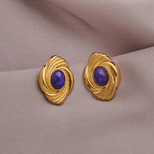 Macro detail of gold vintage swirl earrings with blue turquoise inlay on silk fabric