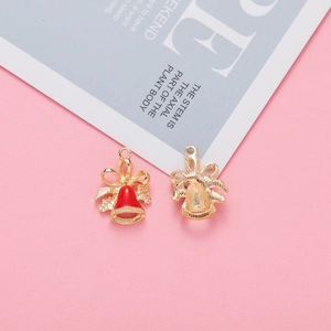 Detail of red enamel Christmas bell pendants with golden bow and metal texture
