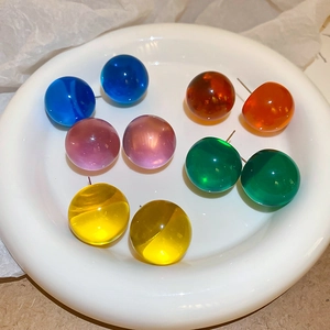 Vue macro de boucles d'oreilles boules en résine colorée dans une coupelle en céramique