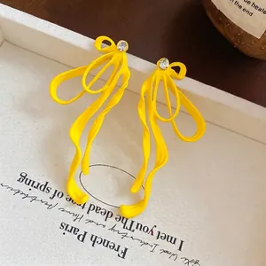 Macro shot of bright yellow bow-knot ribbon earrings with sparkling crystal accents