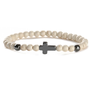 Bracelet en perles de turquoise blanche avec breloque croix en métal gris foncé sur fond blanc