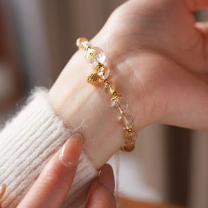 Detail of beaded citrine and quartz bracelet with golden lotus seed pod charm on wrist