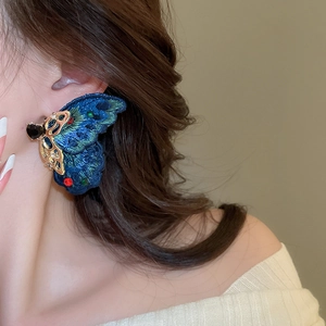 Detail of blue embroidered butterfly earring with colored crystals and gold metal work