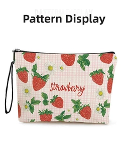 Detalle del neceser de lona con estampados de fresas, diseño de cuadros y cremallera negra