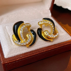 Macro di orecchini vintage in oro con smalto nero e strass brillanti su velluto