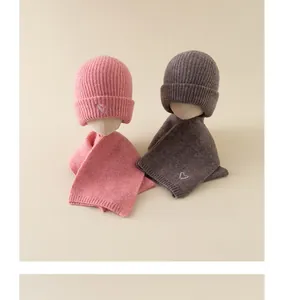 Detailed view of pink and brown knitted baby hat and scarf sets with heart embroidery