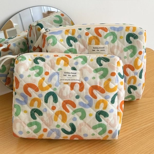 Detail of soft quilted cosmetic bag featuring colorful abstract prints and zipper pull