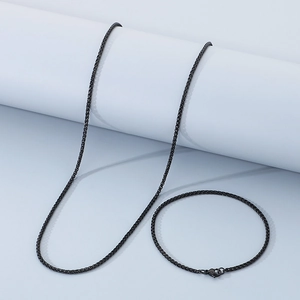 Close-up of black braided stainless steel necklace and bracelet set on a display stand