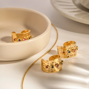 Close-up of three 18K gold-plated rings with hammered texture and colorful gemstones
