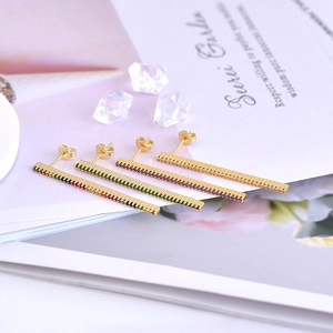 Detail view of colorful zircon crystals on gold rectangular stud earrings on a magazine