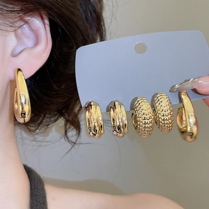 Detail view of various textured golden earrings with wavy and hammered surfaces
