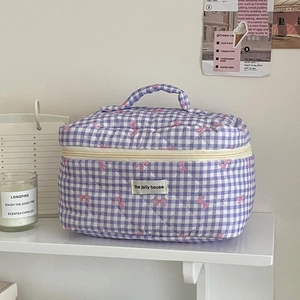 Quilted cotton checkered makeup bag with bow detail and handle on a shelf