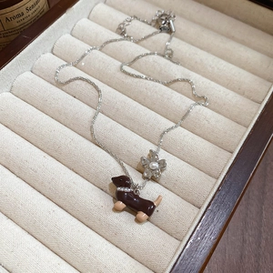 Détail du collier avec pendentifs teckel et fleur avec perles sur plateau à bijoux