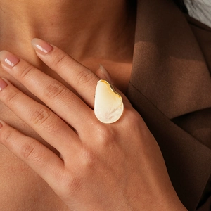 Détail d'une grande bague dorée avec incrustation de résine marbrée sur un mannequin