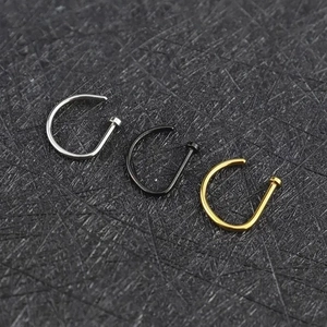 Three D-shaped nose rings in silver, black, and gold colors on a dark background