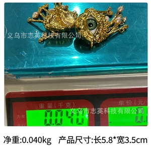 Detailed view showing a gold evil eye brooch weighing 40g and measuring 5.8cm x 3.5cm
