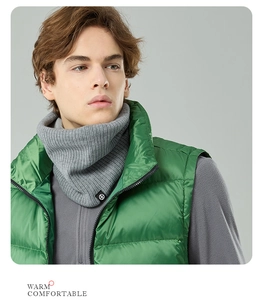 Detail of grey ribbed knit neck warmer with logo tag worn under a green puffer vest