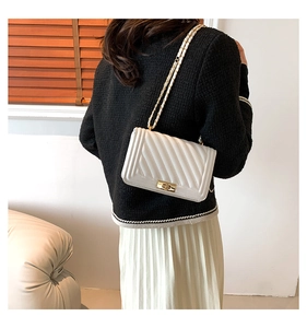 Rear view of model wearing a white V-quilted leather crossbody bag with chain strap