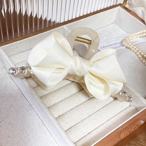 Elegant cream satin bow hair claw clip with rhinestones in a vintage jewelry box