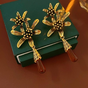 Detailed close-up of antique gold flower earrings with amber teardrop tassels
