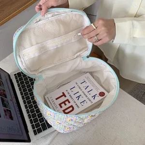 Detail view of floral quilted makeup bag with internal mesh pocket and ample storage space