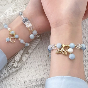 Close-up of ocean blue beaded bracelets with moon, shell, and mermaid tail charms