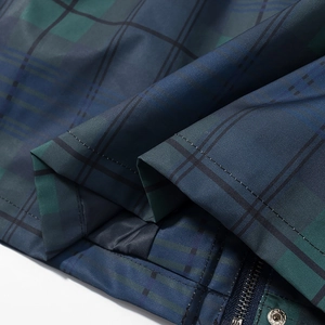 Detail of blue and green plaid jacket featuring durable metal zipper and snap button