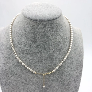 Detail of round white pearl necklace with adjustable 14k gold-plated clasp on display
