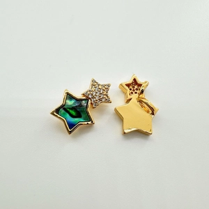 Detail of star-shaped gold-plated pendant with blue abalone shell and pavé zirconia inlay
