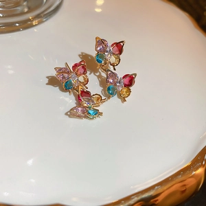 Détail macro de trois boucles d'oreilles papillon dorées avec cristaux multicolores