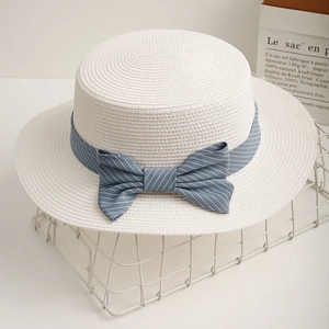 Women's white flat top straw sun hat with blue striped bow on a white wire basket