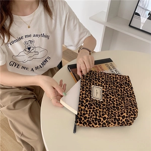 Detailed view of leopard print canvas clutch showing the zipper and branded fabric label