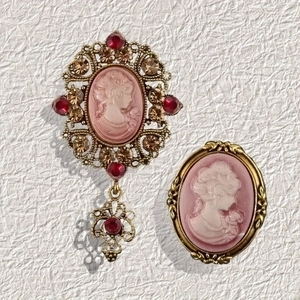 Macro shot of two vintage cameo brooches in antique gold with ruby rhinestones