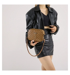 Detail of vintage brown monogram crossbody bag with gold deer charm and adjustable strap